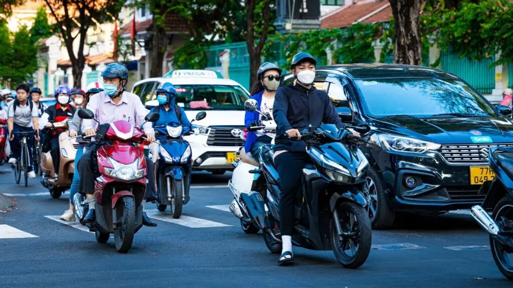 Motorbikes, a Vinasun taxi and a Grab car in Ho Chi Minh City traffic