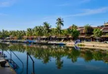 Yellow merchant houses and wooden boats along the Thu Bon river in Hoi An Ancient Town