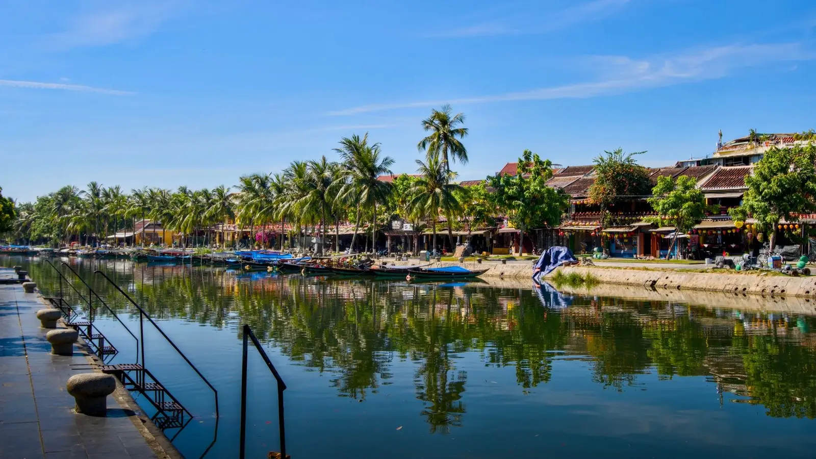 Yellow merchant houses and wooden boats along the Thu Bon river in Hoi An Ancient Town
