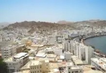 The Reality of Muscat: The Capital That Chose Not to Build Up Aerial view of Muscat coastal city against arid mountains