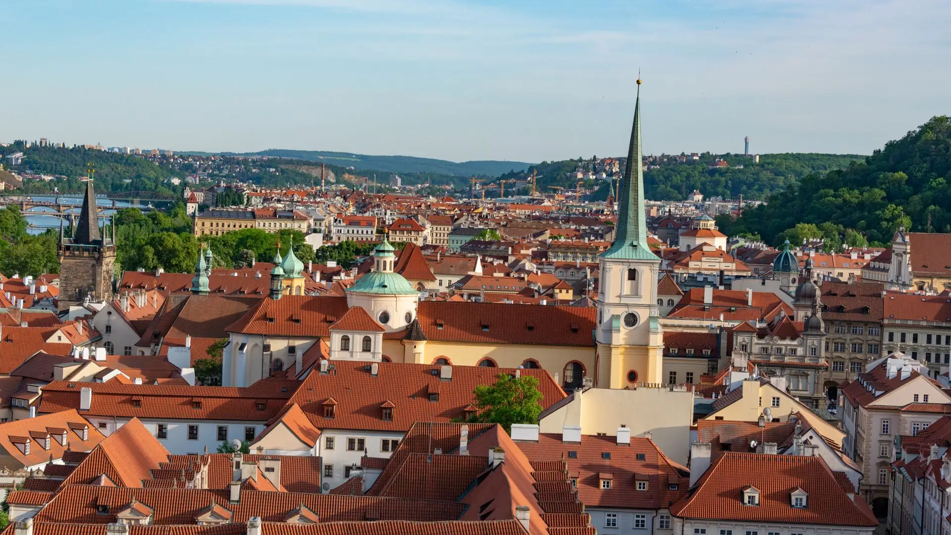 Historic red rooftops of Prague with castle and river beyond